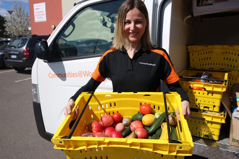 Communities@Work volunteer holding crate of fruit and vegetables.