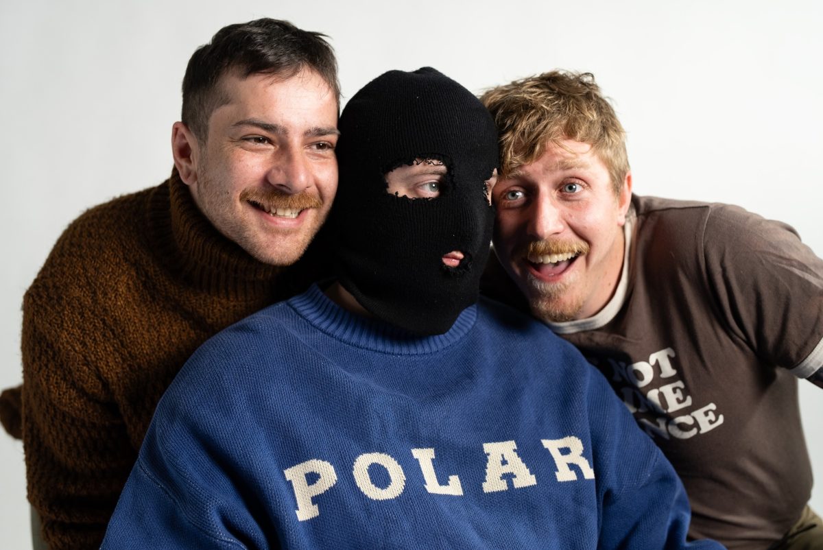 two man smiling and a third man wearing a balaclava