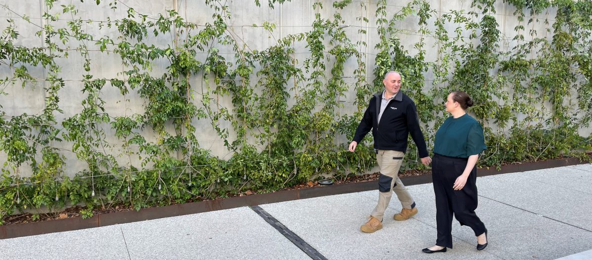 Troy Gowen of Vantage Strata walks by a vine-covered wall with a colleague