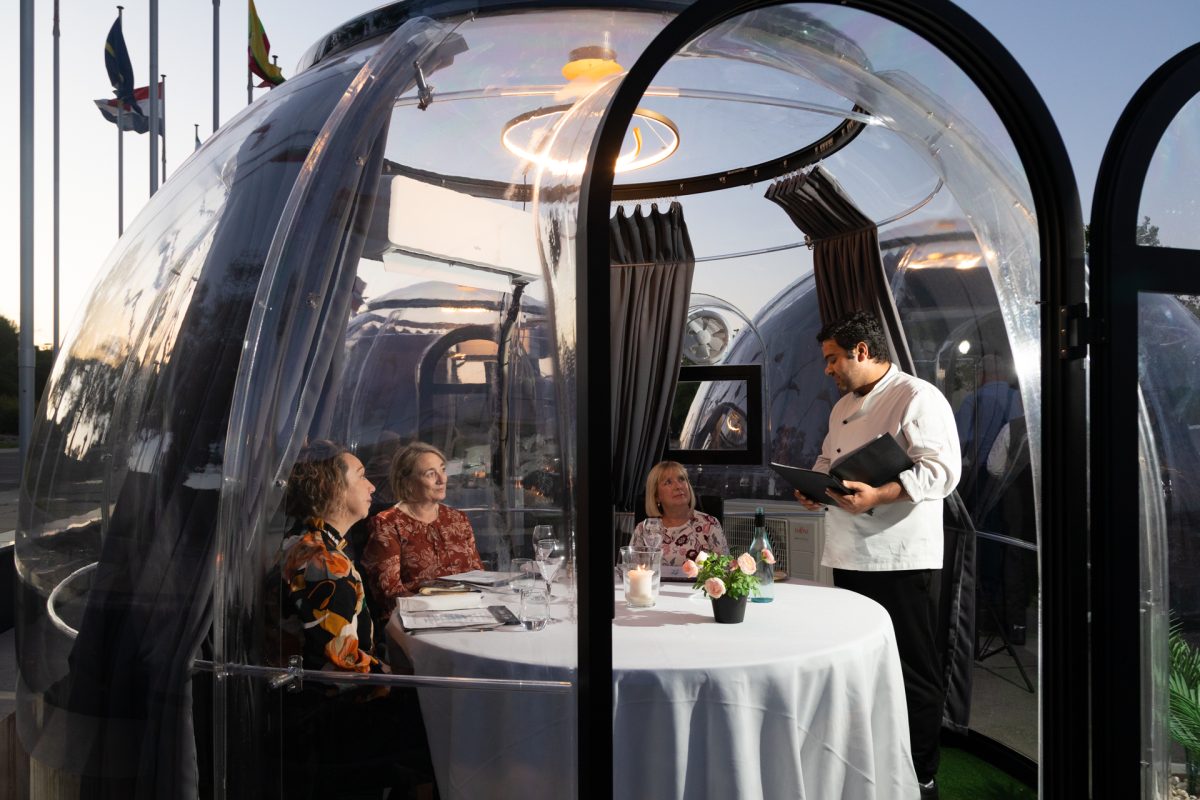 three diners and a waiter in a dining dome 