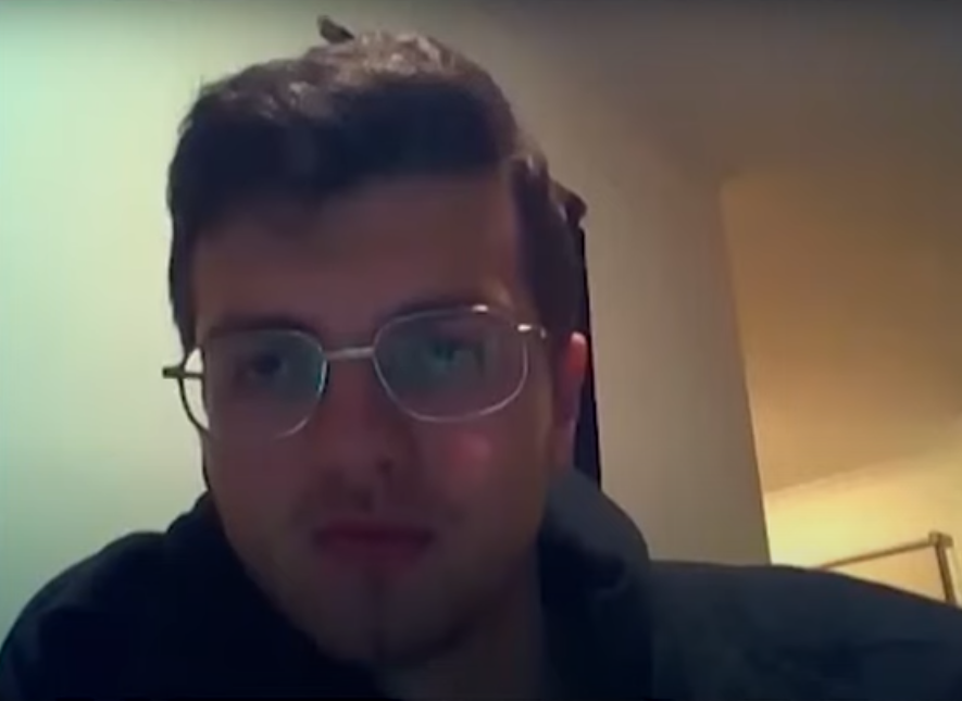 man in glasses sitting in dimly-lit room
