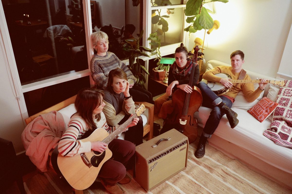 five musicians sitting in a lounge room