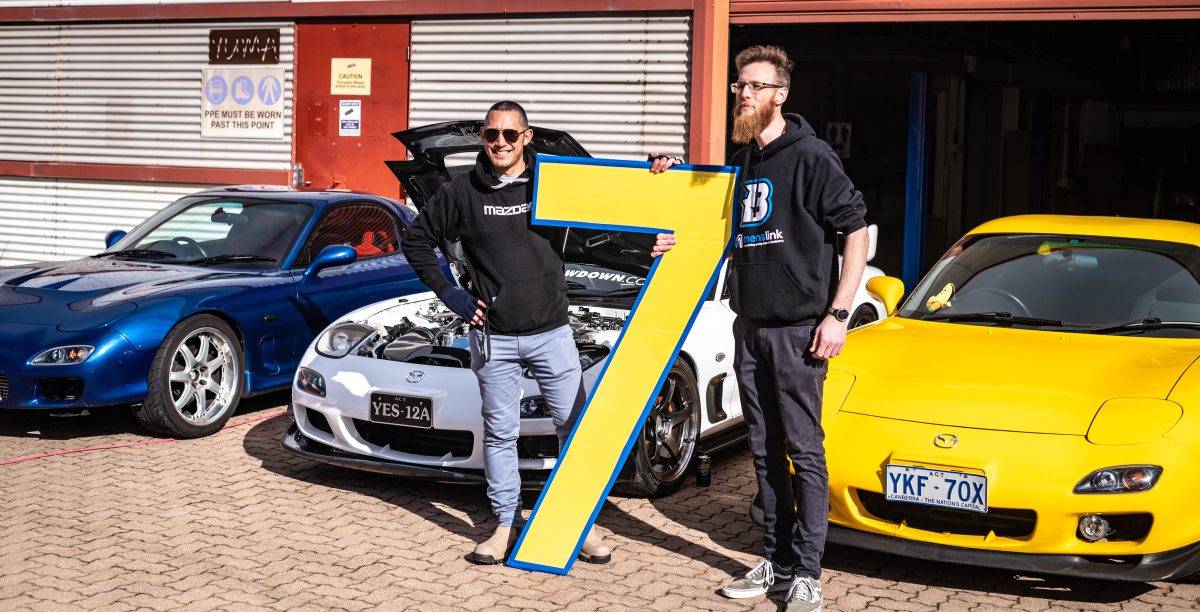 Rob Taylor and his Mazda RX-7 (left) with Mazda car club MazdACT founder Justin Bush (right) hold a giant number seven.