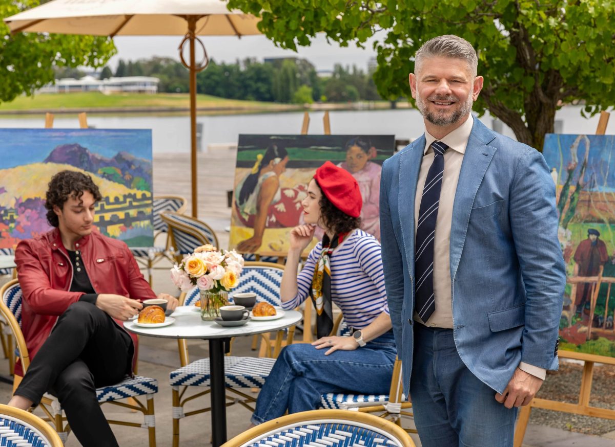 Nick Mitzevich standing in French cafe scene