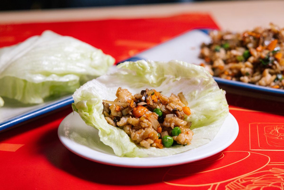 A close up of a dish of san choy bow on a red tablecloth.