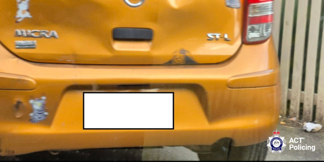 A close-up of the back of an orange car with the number plate covered