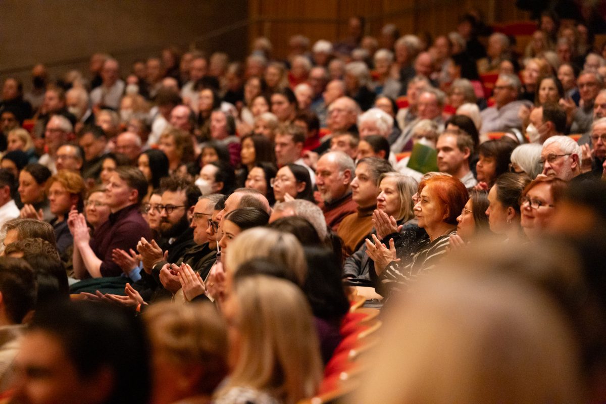 Photo of people sitting at an orchestra and clapping