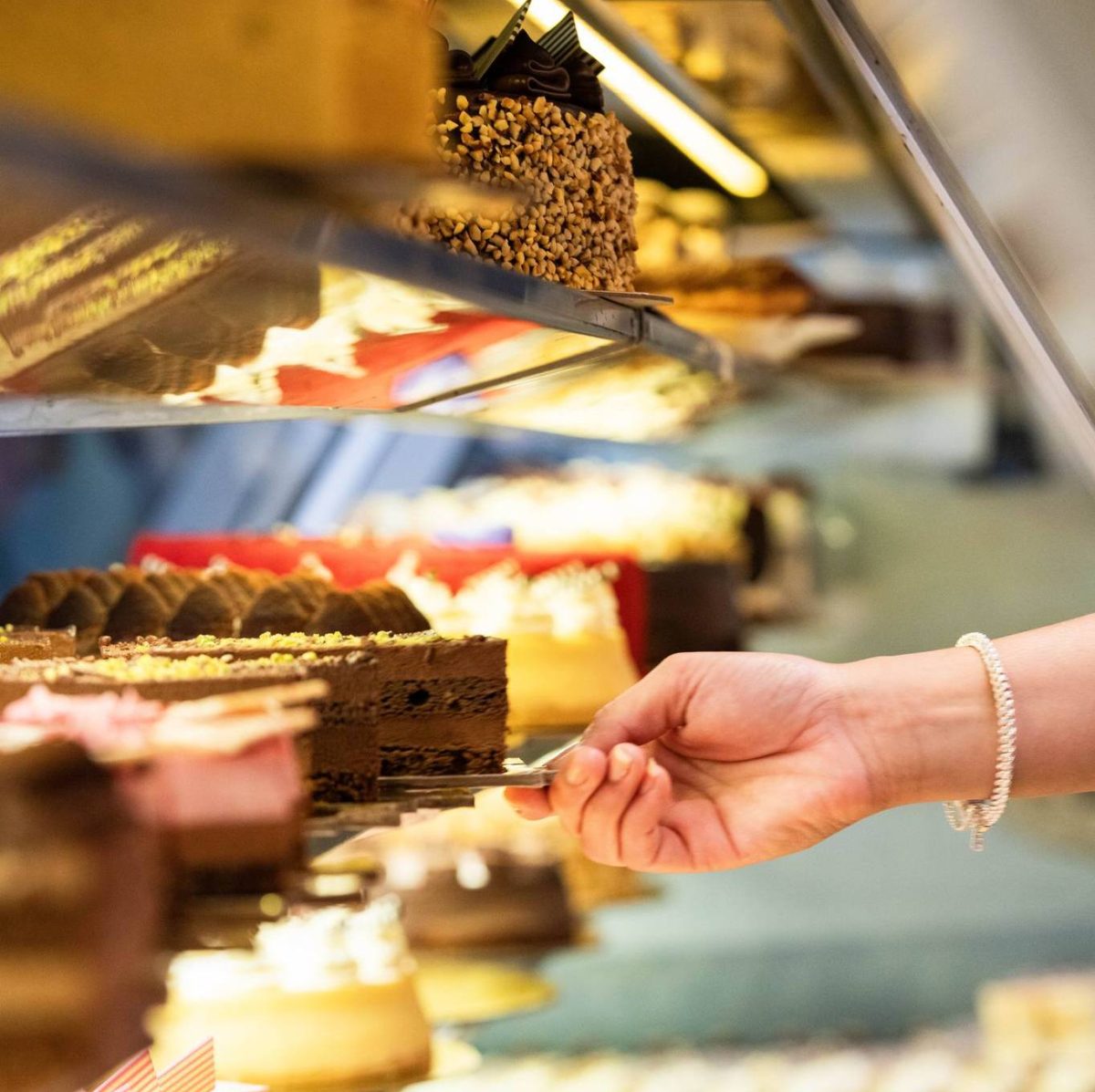 Hand grabs a slice of cake from cabinet.