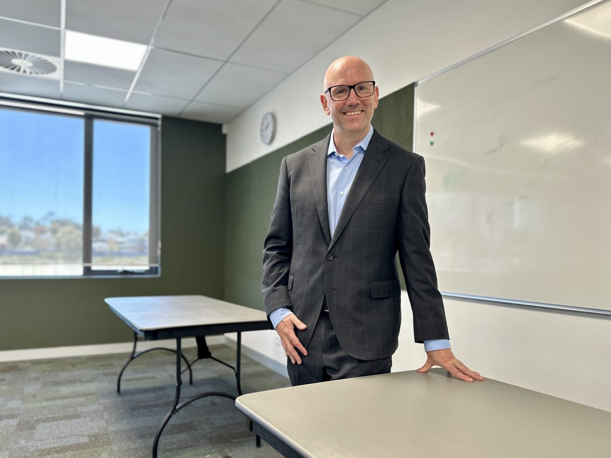 a man standing at a table in a school room