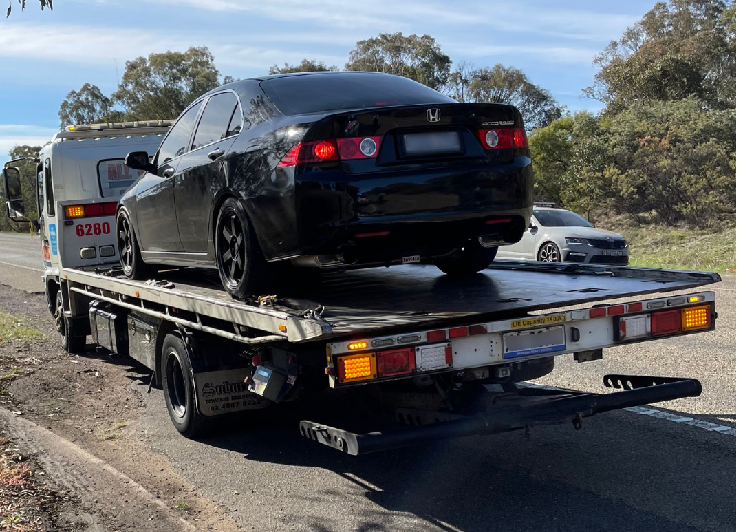 A black Honda Accord on the back of a pick-up truck