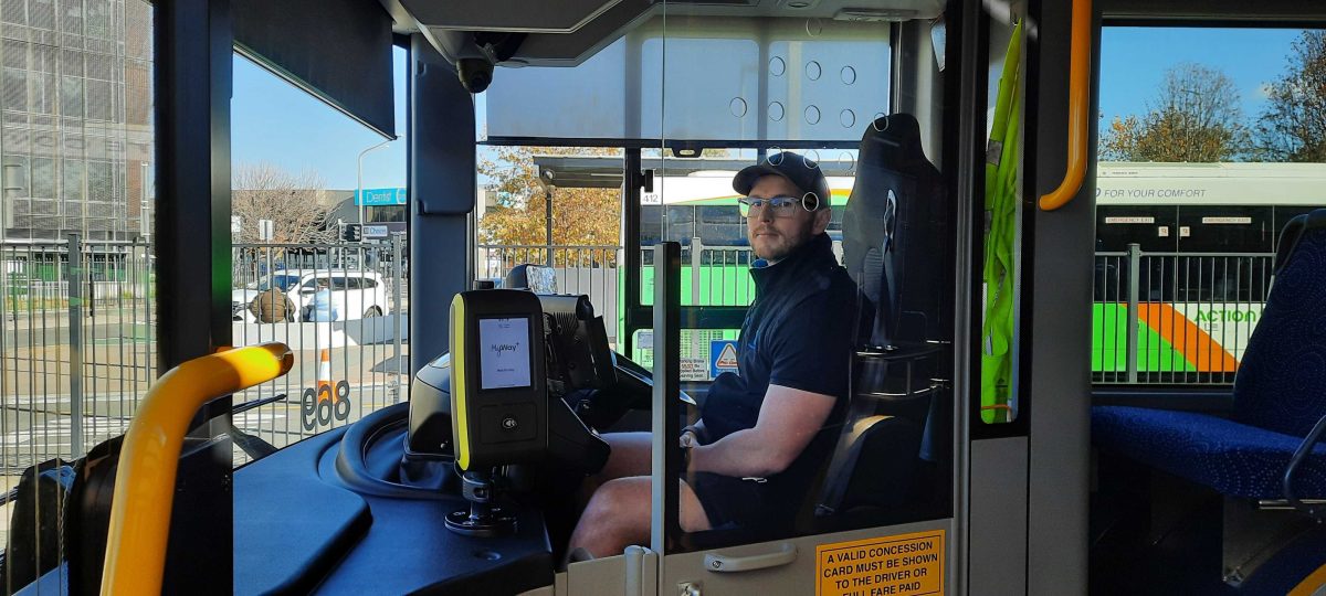 Transport Canberra bus driver Sam Colbert behind a protective screen in one of the electric buses.