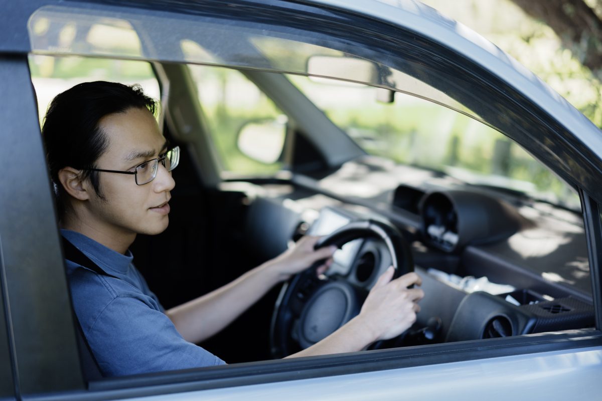 Young Asian man seating at the driver's seat of a right hand drive vehicle