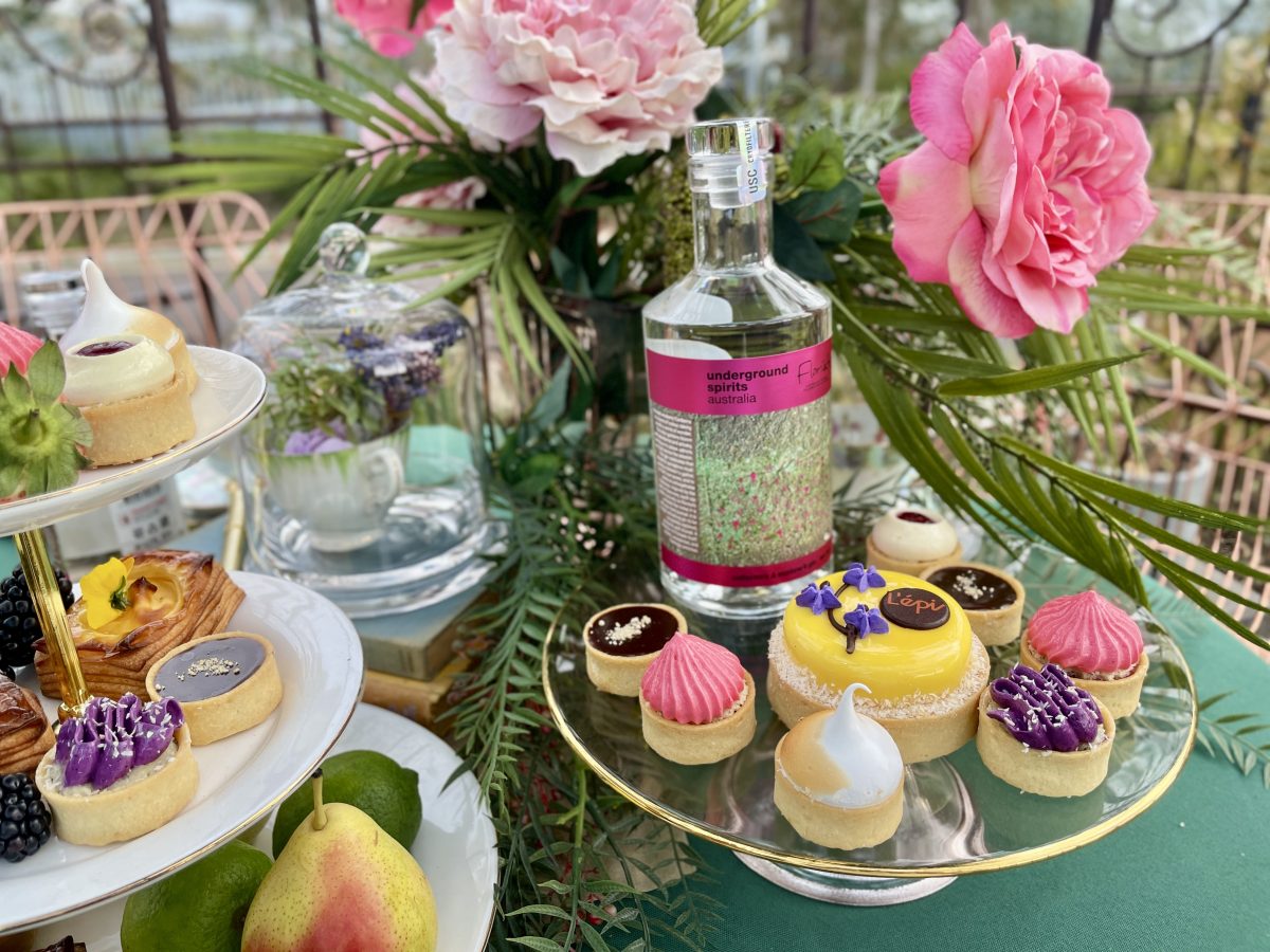 A cake stand with several small tarts and a bottle of Floriade gin.