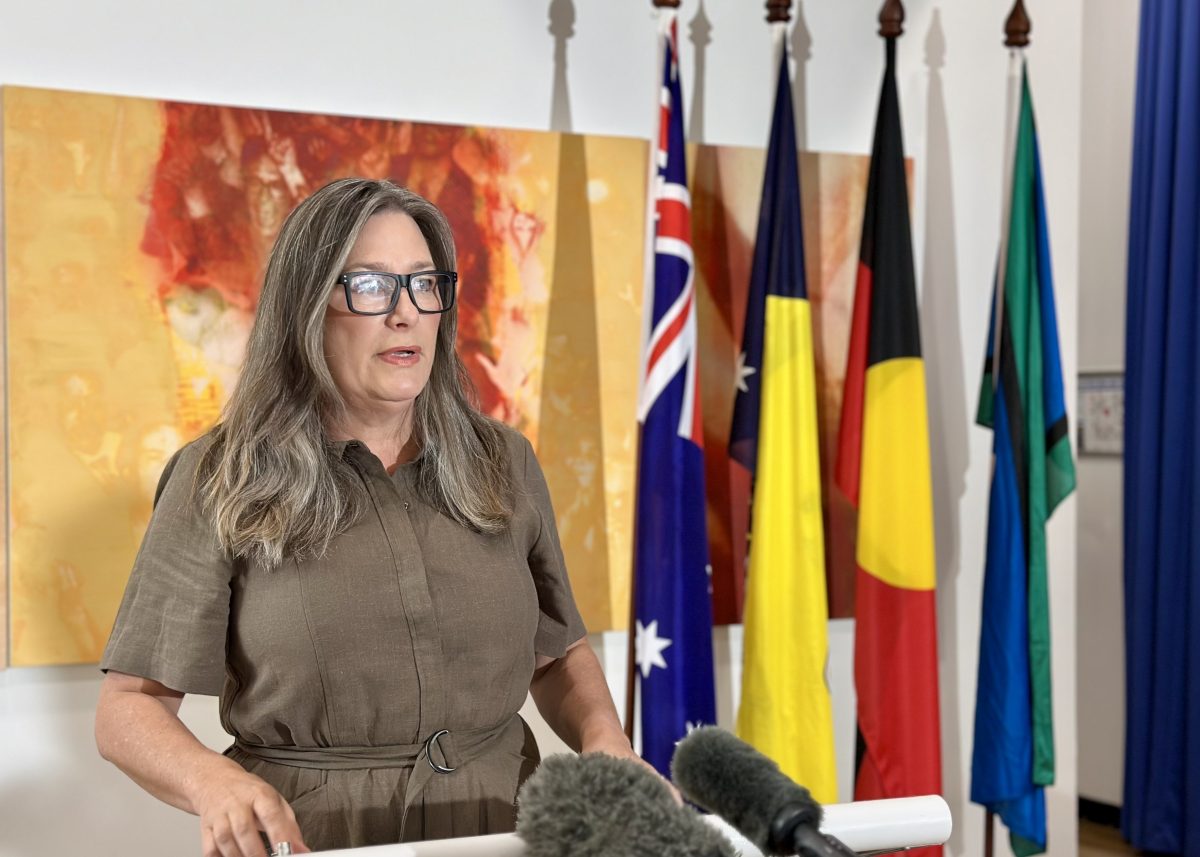 A woman wearing black glasses standing in front of flags