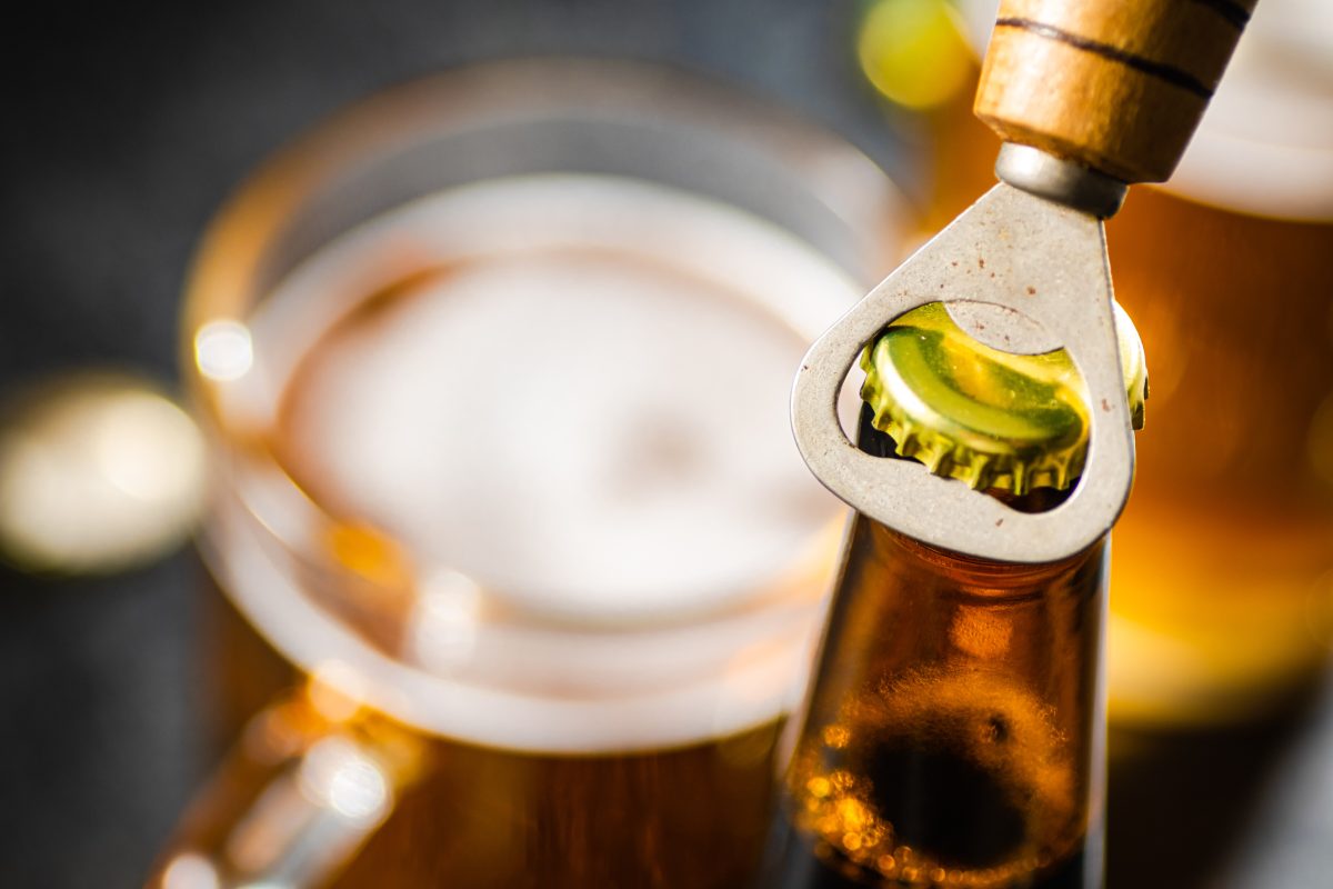 close up of beer bottle being opened