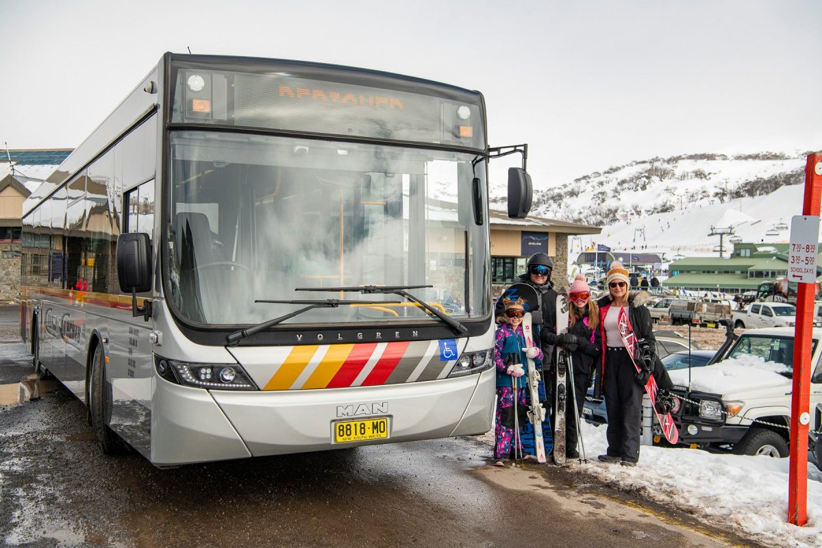 People standing next to a bus at ski resort