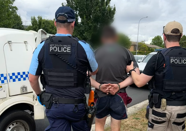 handcuffed man being taken away by police