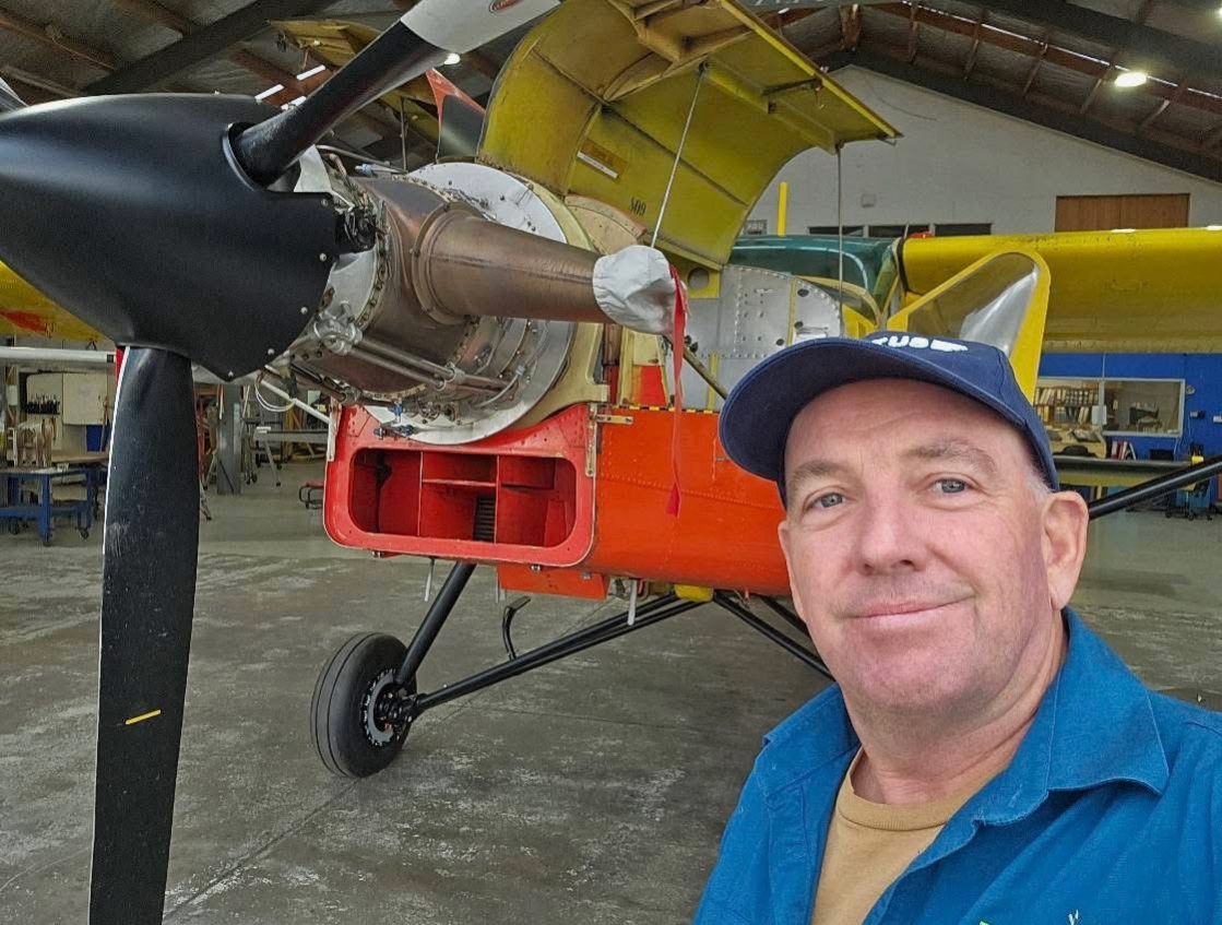 A smiling man standing next to a plane